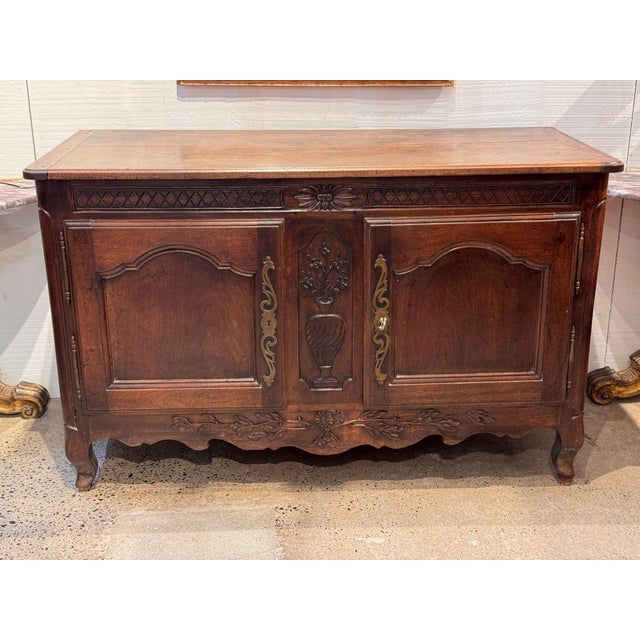 18th century French walnut buffet with a plank top and canted front corners. The frieze is carved with bands of...