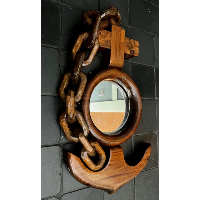 This fun piece is a hand-carved wooden anchor and chain mirror with a nautical folk art aesthetic.
