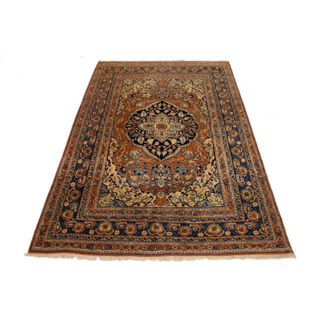 This antique Persian Tabriz rug from the 1920s features a stunning rust field decorated with an intricate floral pattern,...