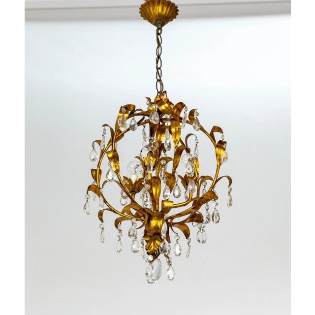 An Italian, gilt metal chandelier in a spherical cage shape. The curling leaves lining the structure dangle octagonal and...