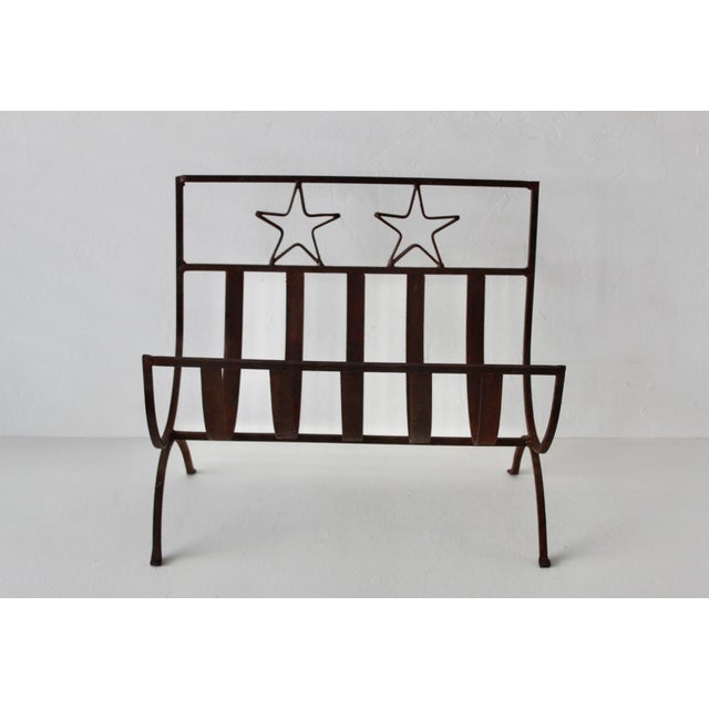 A rustic wrought iron holder features a curved slatted basket base and a decorative top panel accented with two open star...