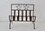 A rustic wrought iron holder features a curved slatted basket base and a decorative top panel accented with two open star...