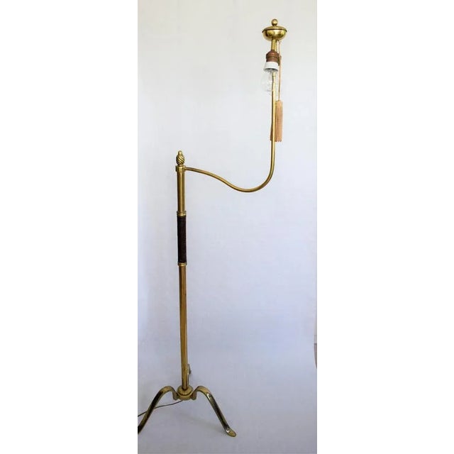 An early 1920s floor lamp attributed to Hugo Gorge, Austria. The lamp has a brass frame with three richly decorated feet...