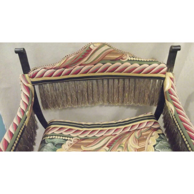 Dramatic iron Savonarola chair with a bronze finish. The colorful new fabric is trimmed with long and lavish fringe in...
