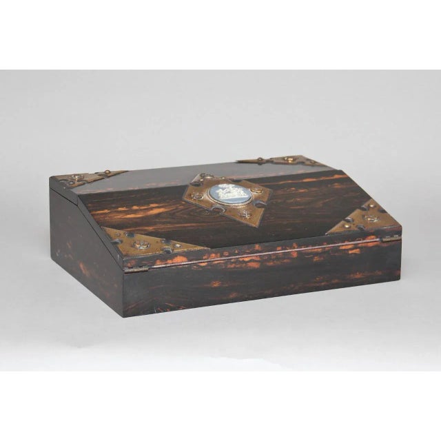 - Coromandel writing slope - Manufactured in the 1880s - Features brass corners and a central brass diamond with a...