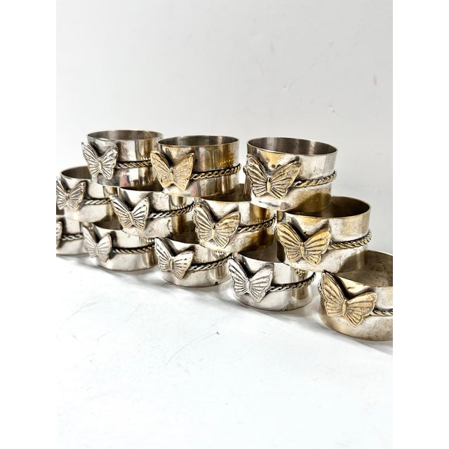 A charming and substantial set of twelve vintage silver napkin rings adorned with sculptural butterfly motifs and twisted...