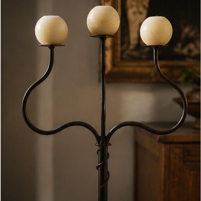 A striking hand-forged wrought iron floor candelabrum dating from the 1990s–2000s, distinguished by its elegant sculptural...