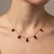 Refined and effortlessly elegant, this Garnet Dangle Station Necklace features five vibrant oval-cut garnet gemstones...