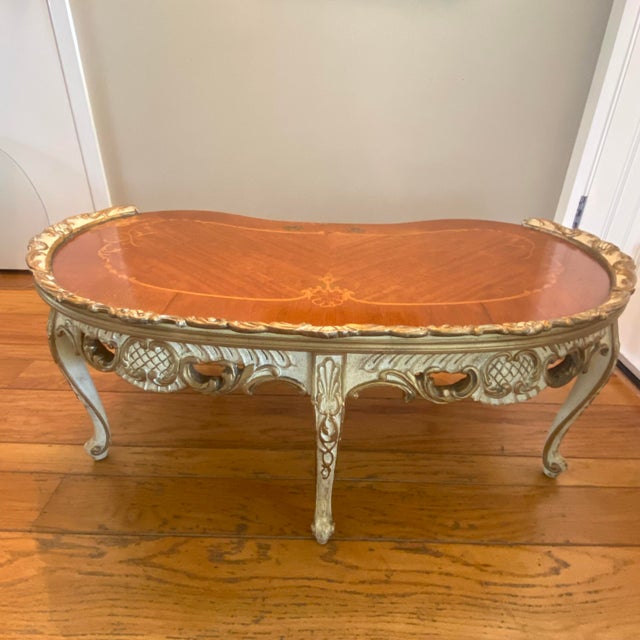 French style coffee table with 5 curved cabriole legs terminating in scroll feet. The apron features ornate, heavily...