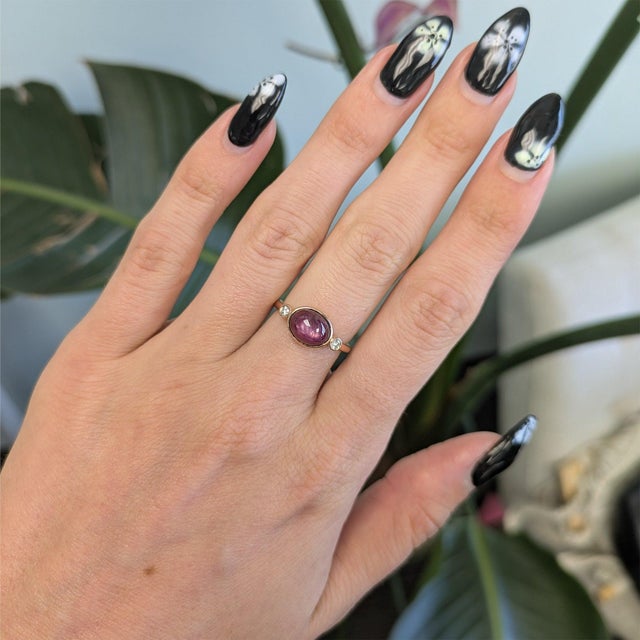 A 3.27-carat star ruby displays a soft six-rayed star across its domed cabochon, set in solid 14K rose gold with two...