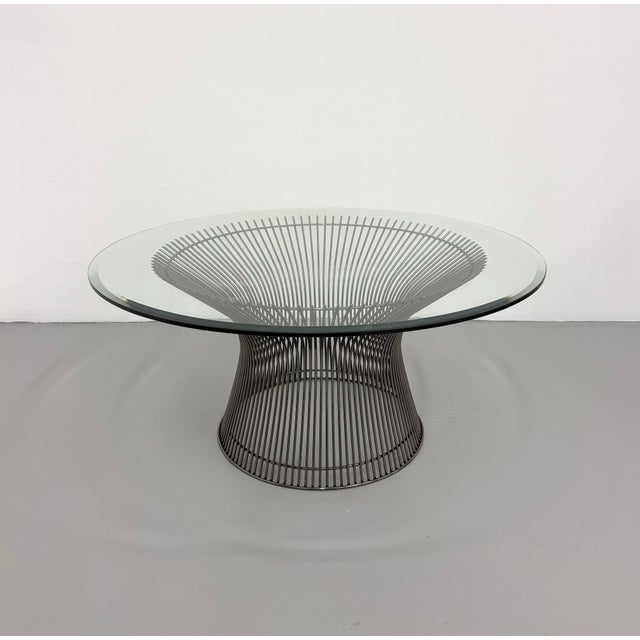 A timeless vintage coffee table in the style of Warren Platner, featuring a sculptural steel wire pedestal supporting a...