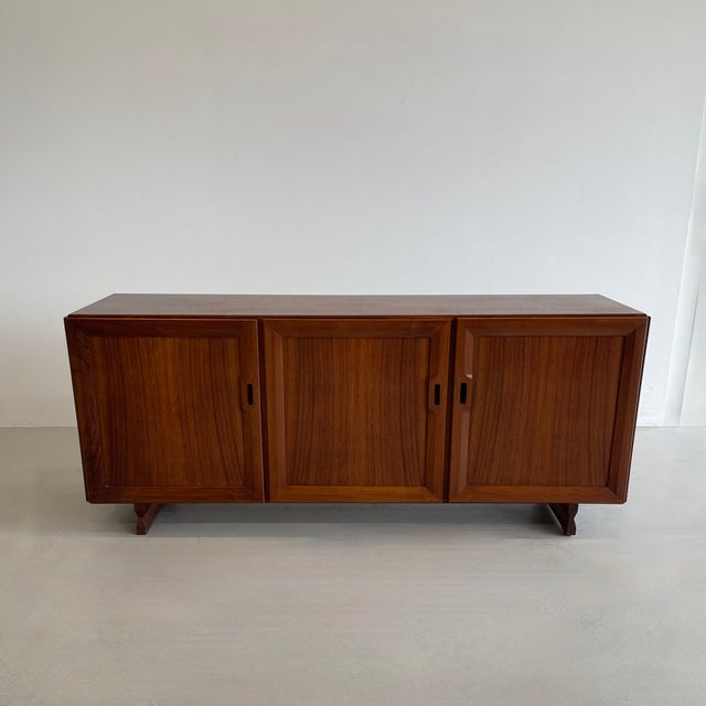The 'MB15' Sideboard with three doors, two compartments with one shelf each, and one compartment with three flat pull-out...