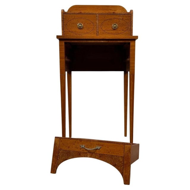 An elegant early 20th-century English cabinet, finely crafted from satinwood and distinguished by its delicate ebony...