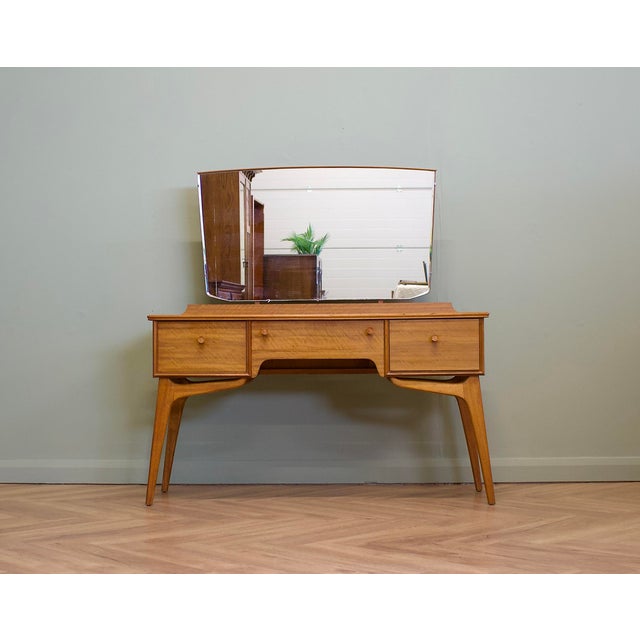 A mid-century walnut dressing table by Alfred Cox, dating from the 1960s. Standing on elegant tapered legs and beautifully...