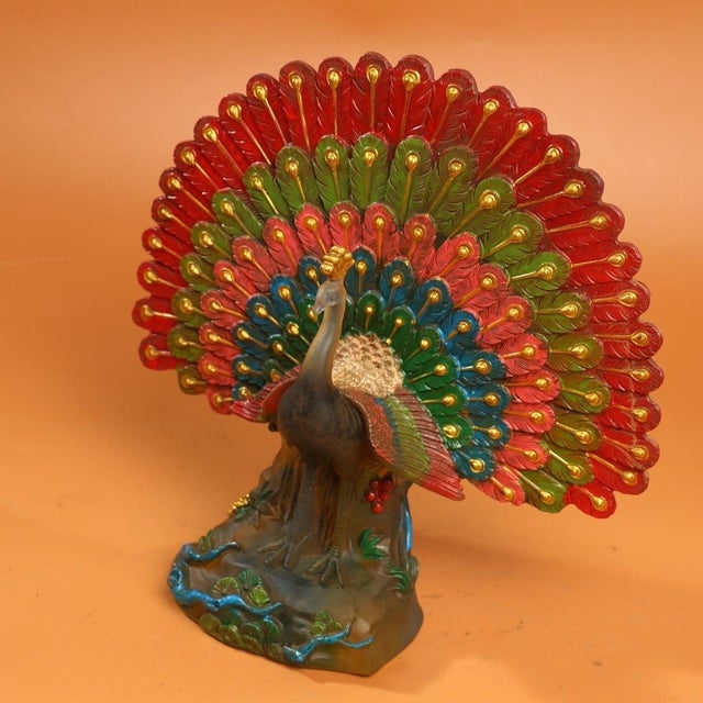 This striking sculpture depicts a peacock with its tail feathers fully fanned in a classic display pose, a traditional...