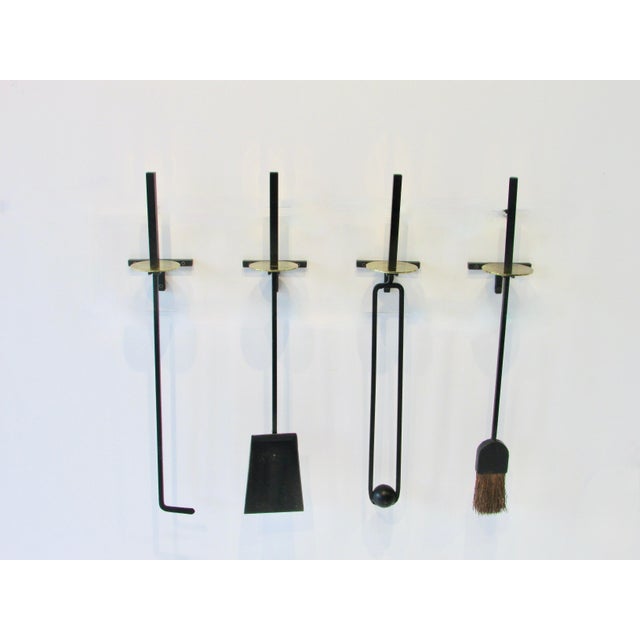 Rare four piece set of Mel Bogart wall mounted fire place tools. Square stock wrought iron tools with brass disc accent....