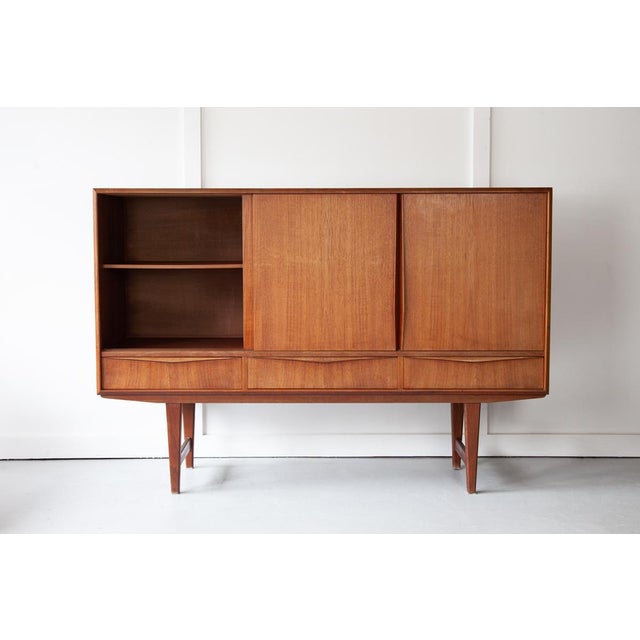 A striking Danish highboard in teak, designed by N. P. Neilsen for Sejling Skabe. The highboard has three sliding doors...