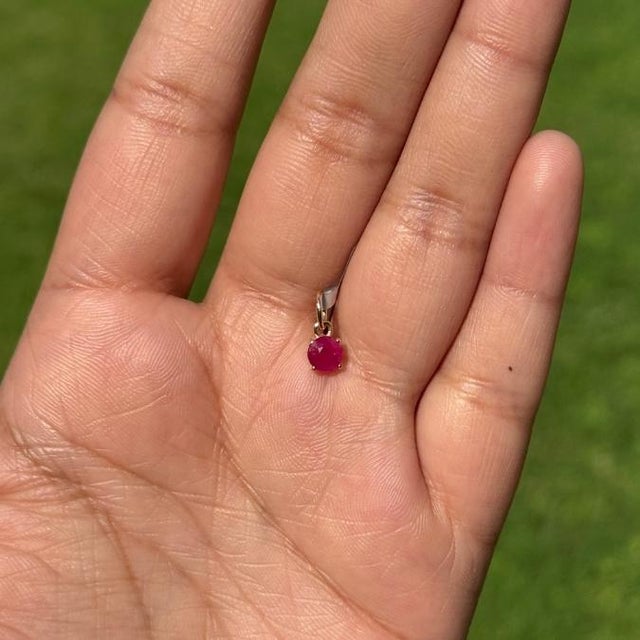 This dainty solitaire pendant features a 0.69 carat natural ruby set in 14K yellow gold. The ruby measuring 4.8 mm,...