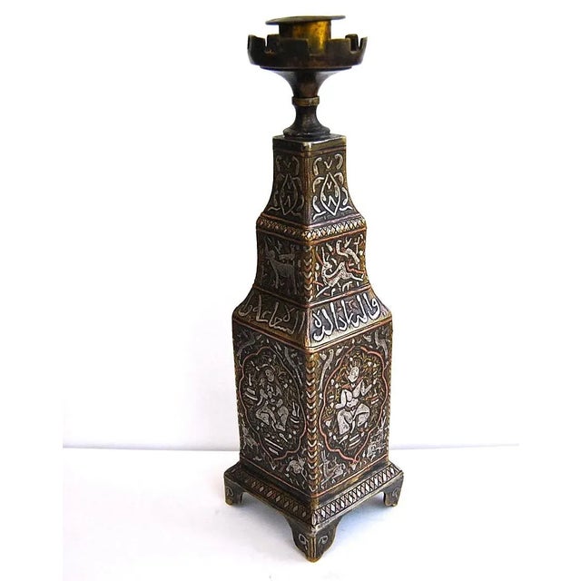 This fine, six-sided brass candlestick has been engraved and inlaid with silver and copper strips in broad bands of Kufic...