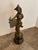 This listing features a bronze patinated cast sculpture of a female figure dressed in Rococo-style attire with a...