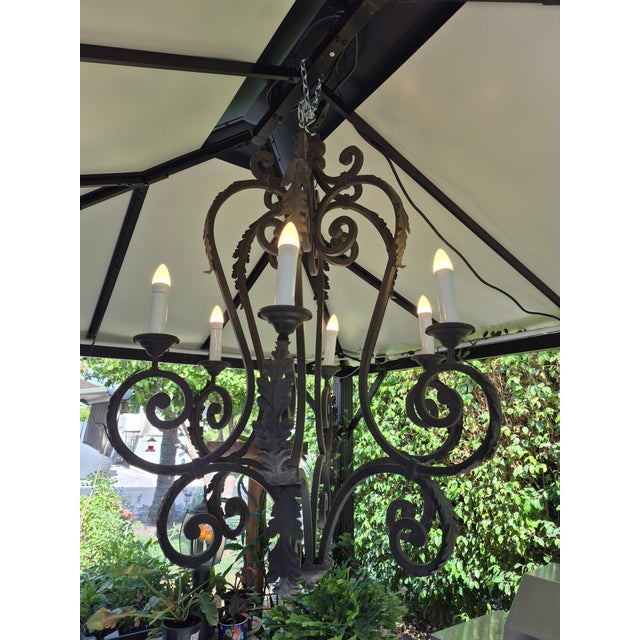 This is a European-style wrought iron chandelier featuring hand-forged scrolled arms and a dark, rustic finish. Design...