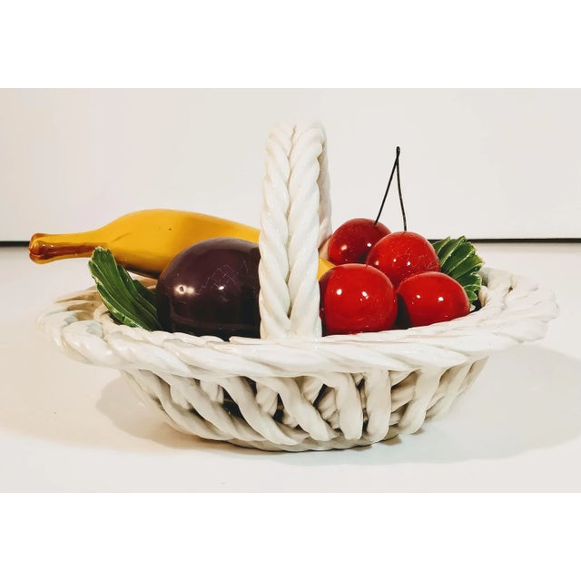 Beautifully designed white basket holding bright colored fruit, all done in the white porcelain pottery that region is...