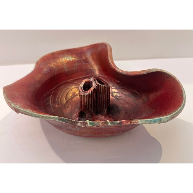 A raku-style ceramic vessel designed for flower arranging, with a wide, organic, free-form rim that curves and folds...