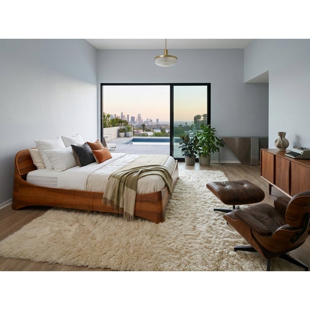 This 1970s bed frame is a masterclass in italian woodworking, defined by the seamless elegance of curved walnut-veneered...