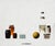 In "Origami," a serene composition unfolds with a minimalist arrangement of everyday objects, including jars, a bottle,...