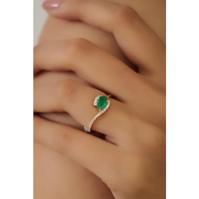 This bypass ring features a 0.49 carat pear-shaped emerald set in 14K yellow gold. The emerald measuring 5 x 8 mm, secured...