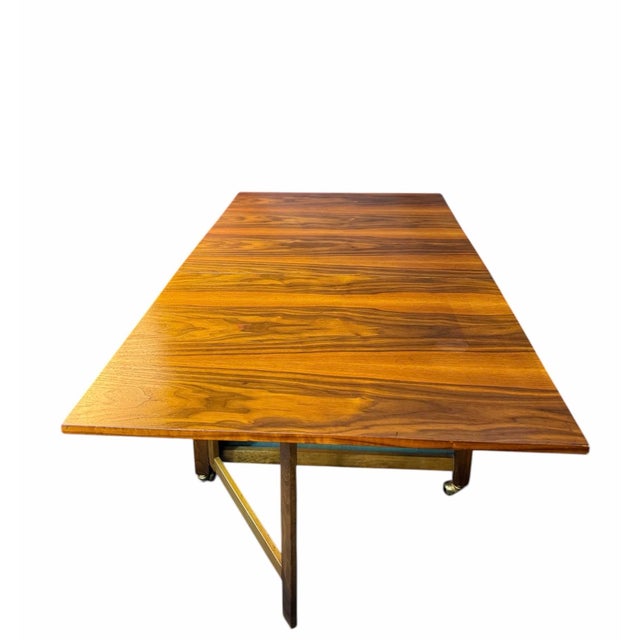 A well-crafted, compact teak drop-leaf dining table featuring convenient built-in storage and casters for easy mobility....