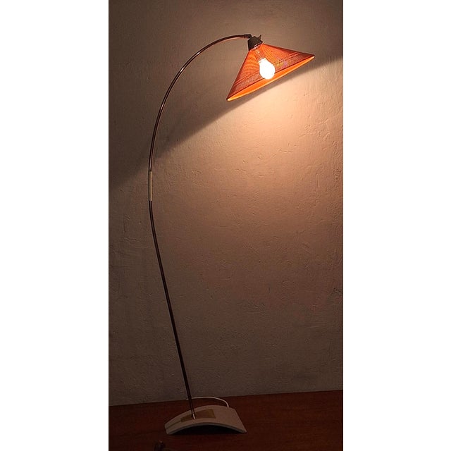 Arc floor lamp in brass with a perforated metal adjustable shade and unusual curved grey metal foot, dating from the...