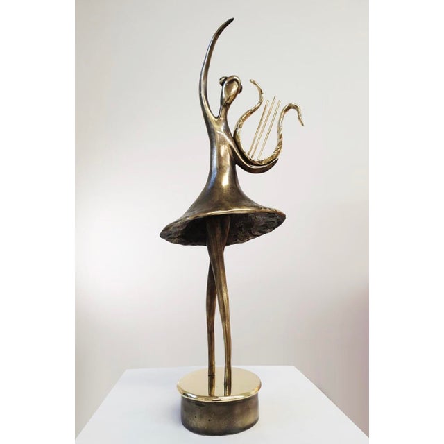 A contemporary figurative bronze of a dancer with a lyre, poised on tiptoe with one arm sweeping high overhead, her skirt...