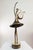 A contemporary figurative bronze of a dancer with a lyre, poised on tiptoe with one arm sweeping high overhead, her skirt...