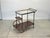 1960s bar trolley, black lacquered iron and brass structure, wooden and glass tops, height at the top 70 cm.