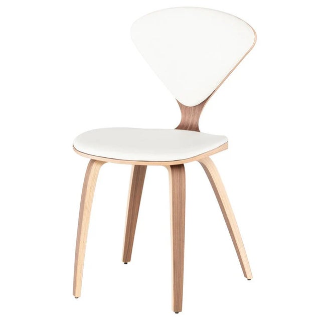 Nuevo Satine dining chairs featuring white leather seats and an American walnut finish. Crafted with bent plywood...