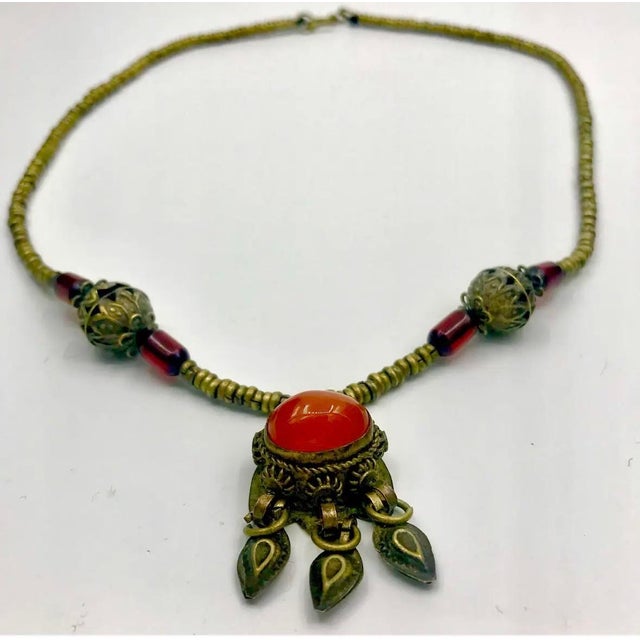 A distinctive vintage Himalayan-style necklace featuring a substantial oval carnelian cabochon suspended from a chain of...