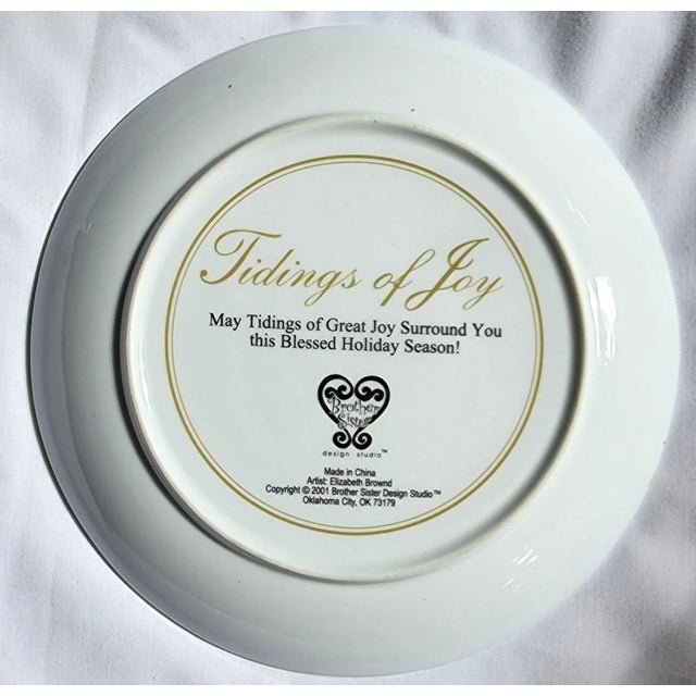 This Royal Doulton porcelain plate is framed with a garland of holly, roses, mistletoe and pine, rimmed with gold. The two...