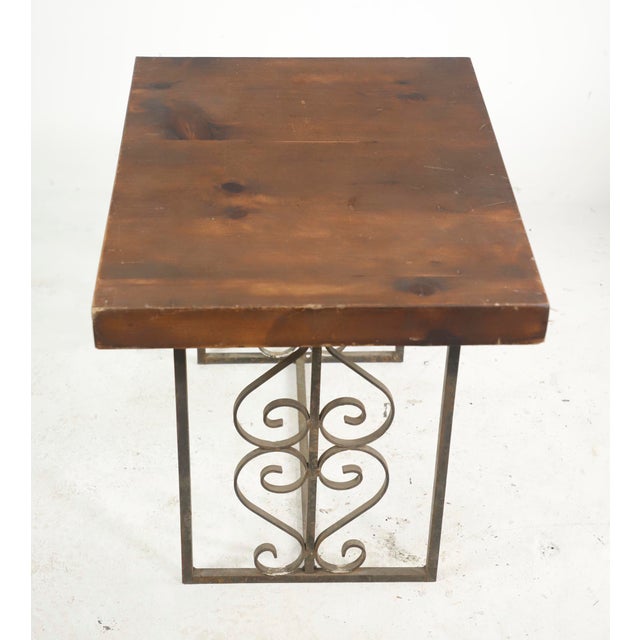 Reclaimed pine wood table top on a wrought iron base. Heart and scroll motifs are featured on the base, complemented by...