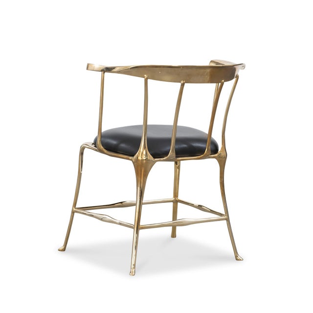 Polished brass accent chair with black leather seat. Inspired by Salvador Dali, this striking accent chair is a piece of...