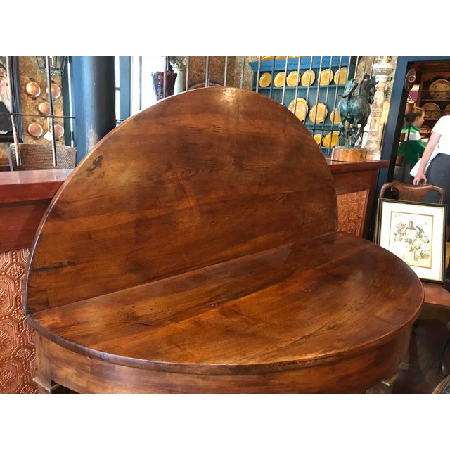 An elegant and versatile early 19th-century French Demi-lune, oval dining table crafted from solid cherrywood. The table...
