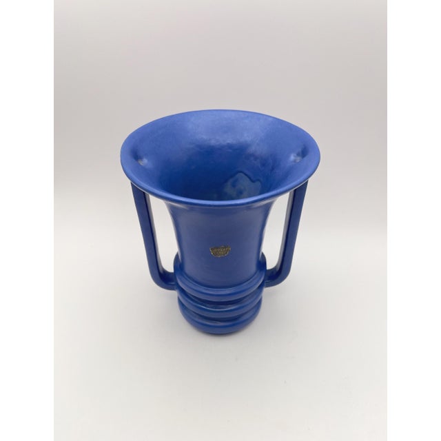 A vintage Camark Pottery vase in a rich matte blue glaze, standing 6.75" tall. The bold trumpet form, stepped base, and...