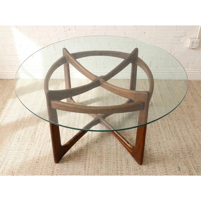A striking 1960s dining table attributed to Adrian Pearsall, featuring a sculptural wood base beneath a substantial round...