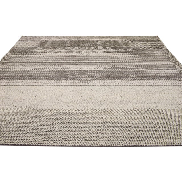 This hand-knotted wool rug boasts a modern Texture-style aesthetic, boasting a classic beige field with minimalist gray-...