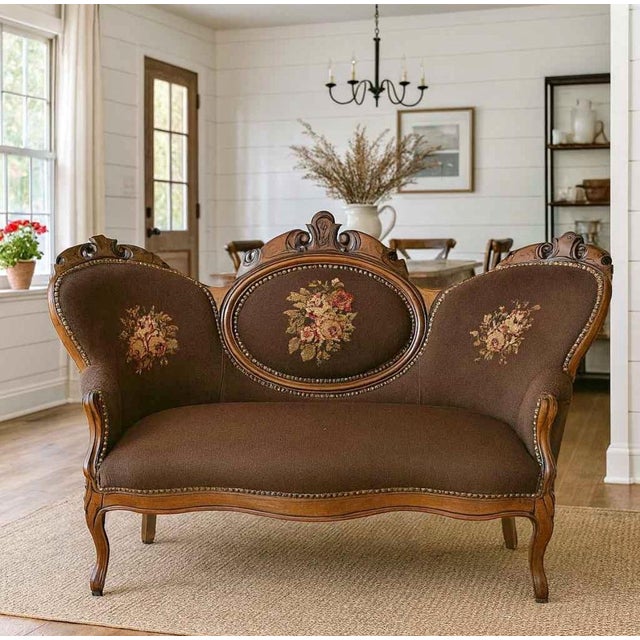 A charming antique settee featuring beautifully detailed European floral needlepoint upholstery and graceful carved wood...