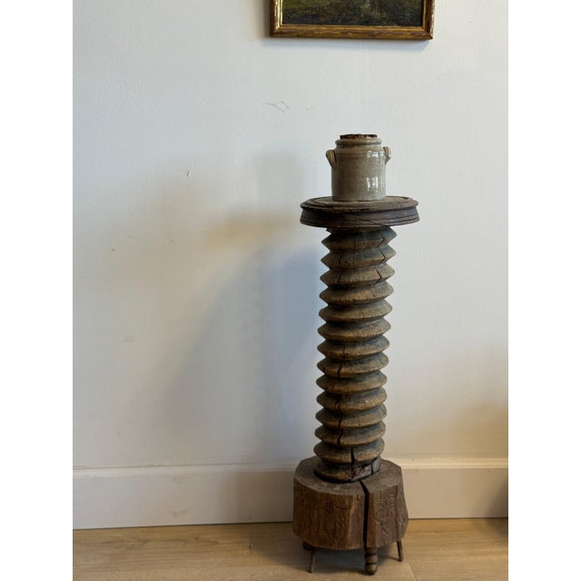 A striking antique French wine press screw repurposed as a sculptural pedestal, with its deeply carved helical shaft...