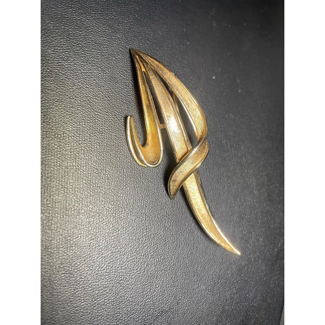 Capturing the sleek, sculptural spirit of Mid-Century Modern design, this vintage Trifari brooch features a soaring,...
