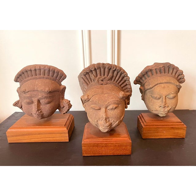 A collection of three carved sandstone heads on wood display stands from Northern India Rajasthan or Madhya Pradesh, circa...