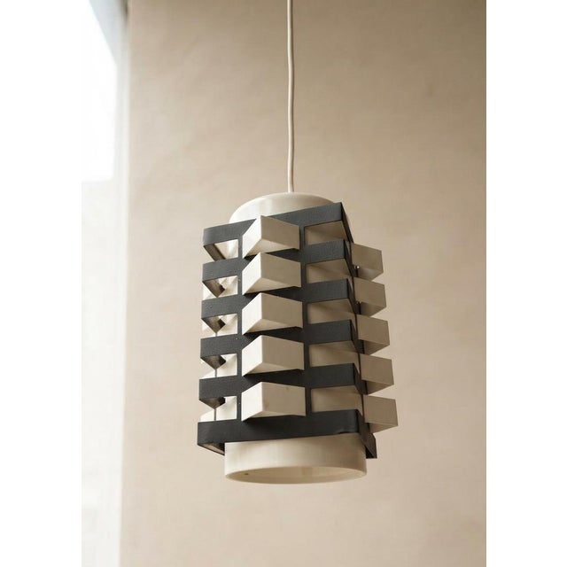 A distinctive vintage table lamp from the 1970s, featuring a sculptural cylindrical metal shade formed by a series of...
