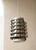 A distinctive vintage table lamp from the 1970s, featuring a sculptural cylindrical metal shade formed by a series of...